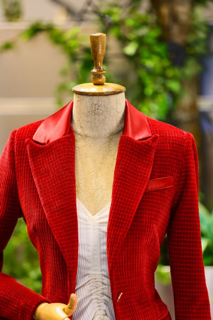 Red checkered blazer on a mannequin with a leather collar, showcasing elegance in fashion photography.